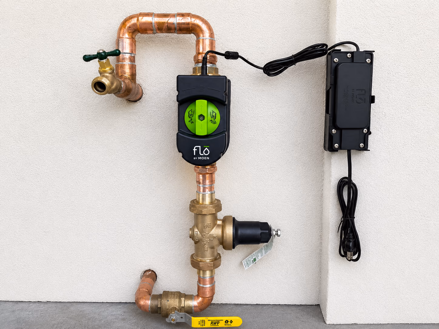 Moen Flo smart automatic water shut-off device installed on a residential copper main line with brass hose bib and wall-mounted control box